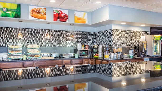 A modern breakfast bar with a patterned backsplash, a variety of food items, and a digital menu display.