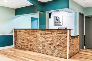 Un mostrador de recepción con fachada de piedra y un letrero que dice 'Quality by Choice Hotels'.