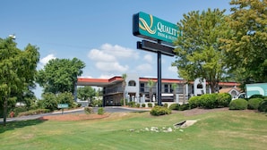 A hotel with a green sign reading "Quality Inn & Suites" and a covered parking area.