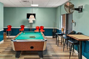 A pool table in a room with teal walls, red chairs, and a table with chairs. - Quality Inn & Suites Aiken East (Aiken)