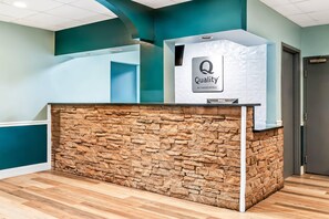 A reception desk with a stone facade and a sign that reads 'Quality by Choice Hotels'. - Quality Inn & Suites Aiken East (Aiken)