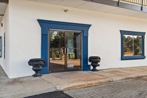 Entrada de un edificio con una puerta de cristal y dos jarrones negros a cada lado.