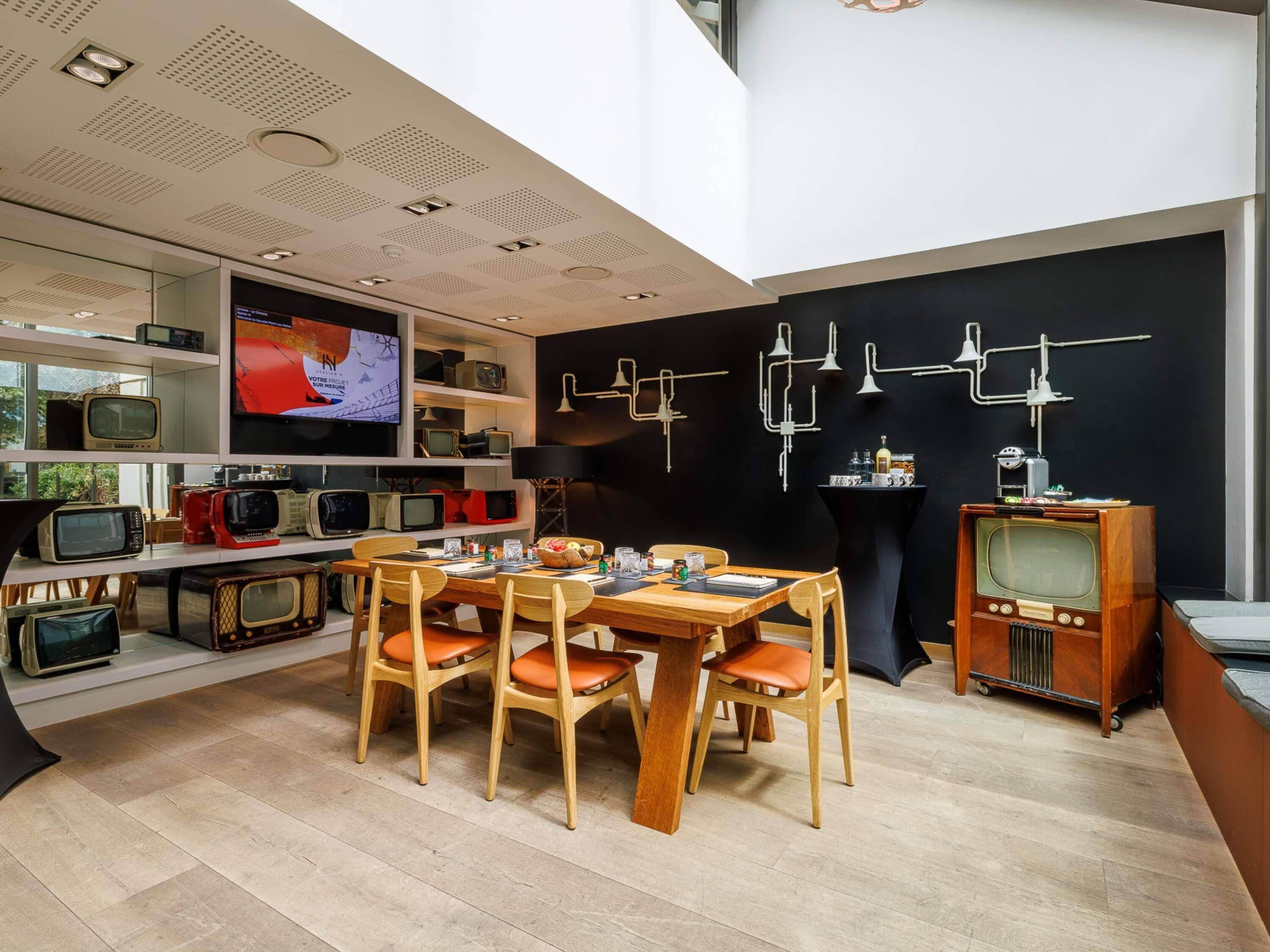 A modern interior with a dining area, a wall-mounted TV, and a collection of vintage TVs.