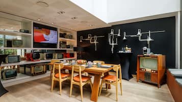 Un interno moderno con zona pranzo, TV a parete e una collezione di televisori d'epoca.
