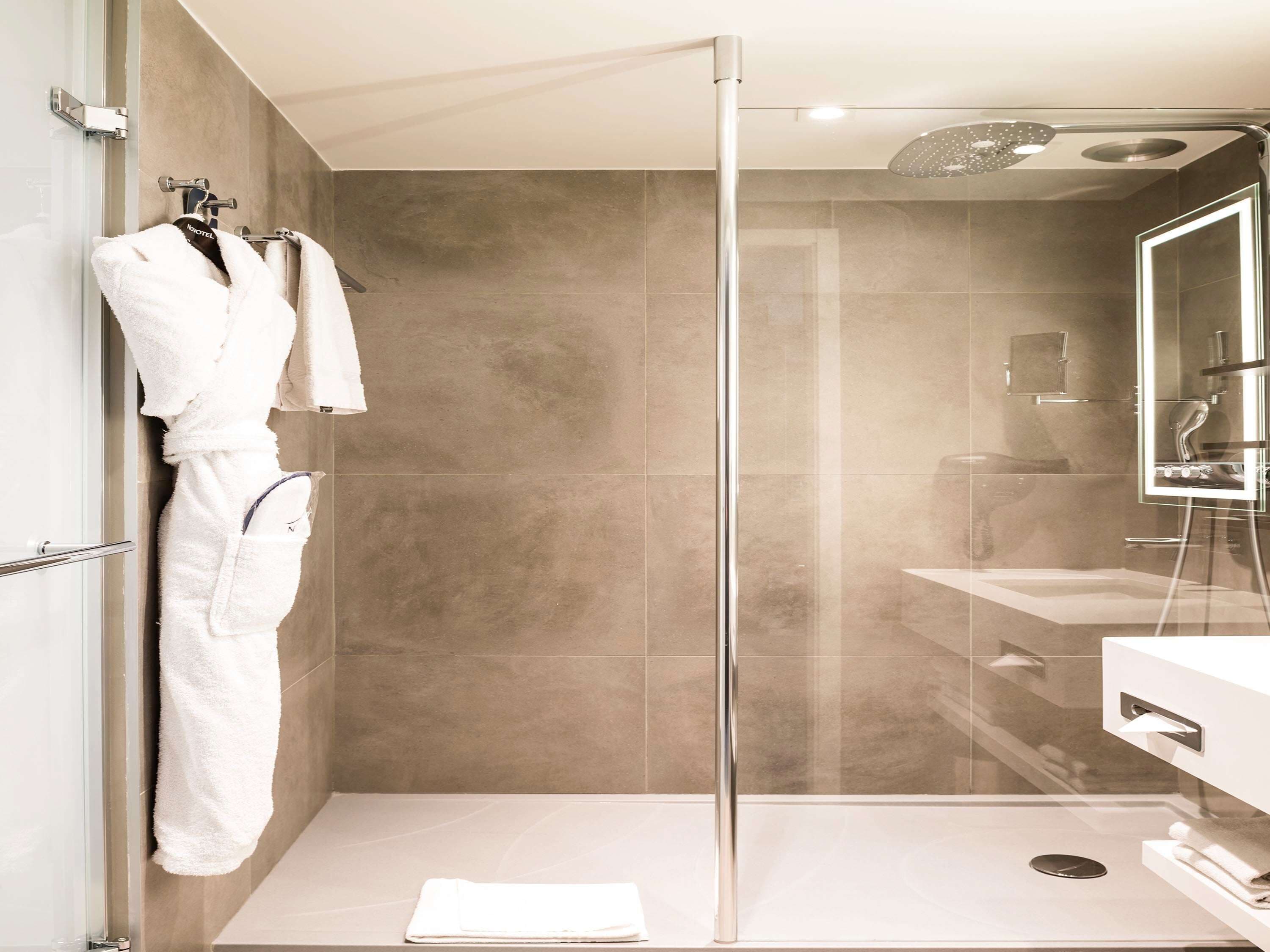 A modern shower with a glass door, a white sink, and a mirror.