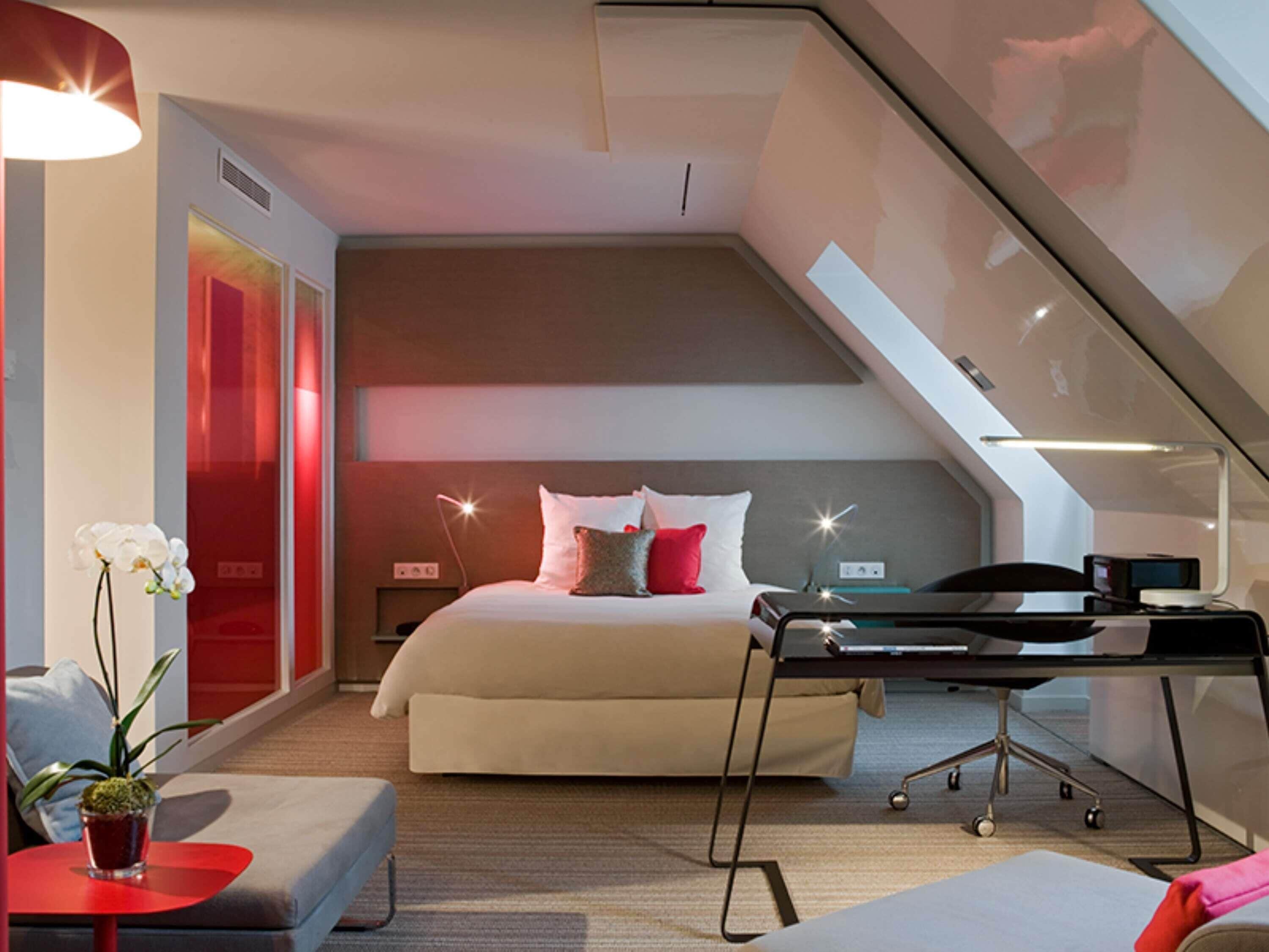 A modern bedroom with a bed, bedside table, desk, and chair.