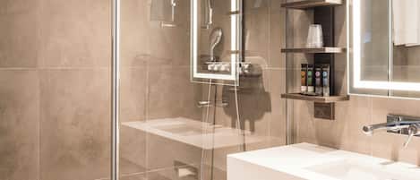 A modern bathroom with a glass-enclosed shower, a large mirror, and a white sink.