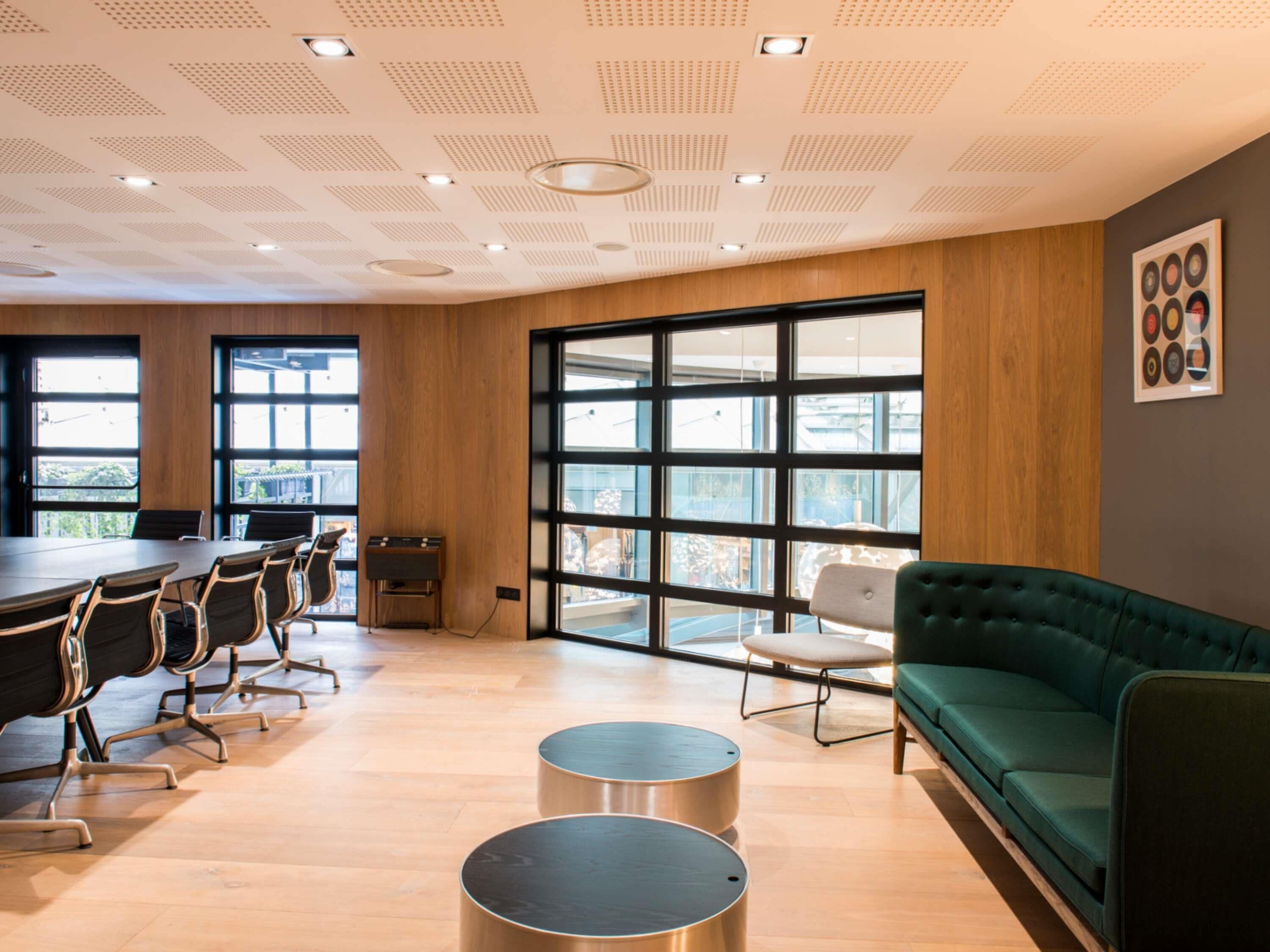 A modern meeting room with a large table, chairs, a sofa, and large windows.