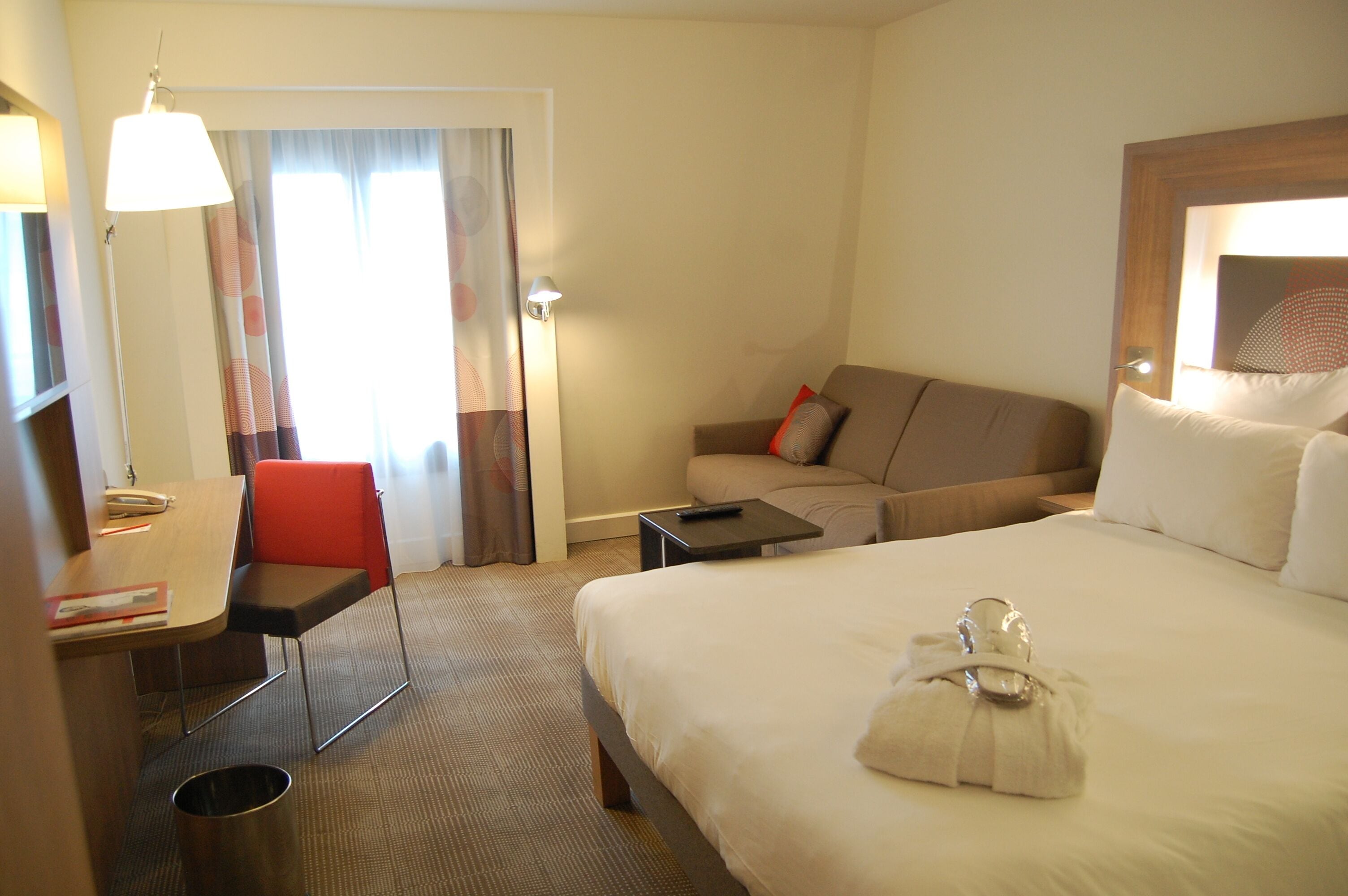 Una camera d'albergo con un letto, una scrivania, una sedia, un divano e un tavolino.