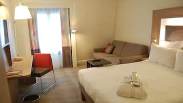 Una camera d'albergo con un letto, una scrivania, una sedia, un divano e un tavolino.