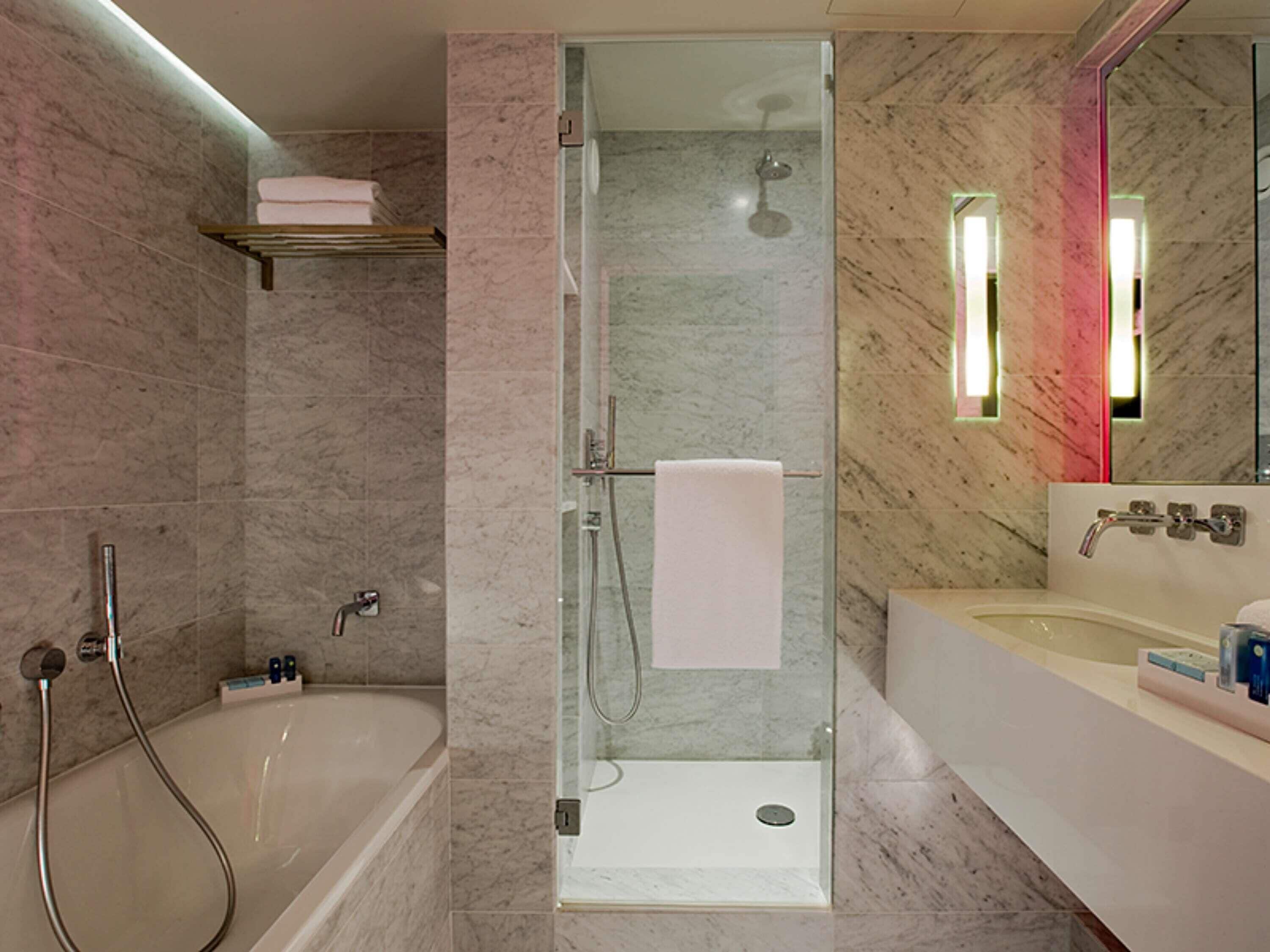 Une salle de bain moderne dotée d’une douche à parois de verre, d’une baignoire sur pieds et d’un meuble-lavabo avec un miroir.