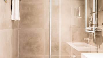 Un baño moderno con cabina de ducha de vidrio, lavamanos blanco y espejo.