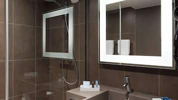 A modern bathroom with a shower, a large mirror, and a vanity with a sink and towel storage.