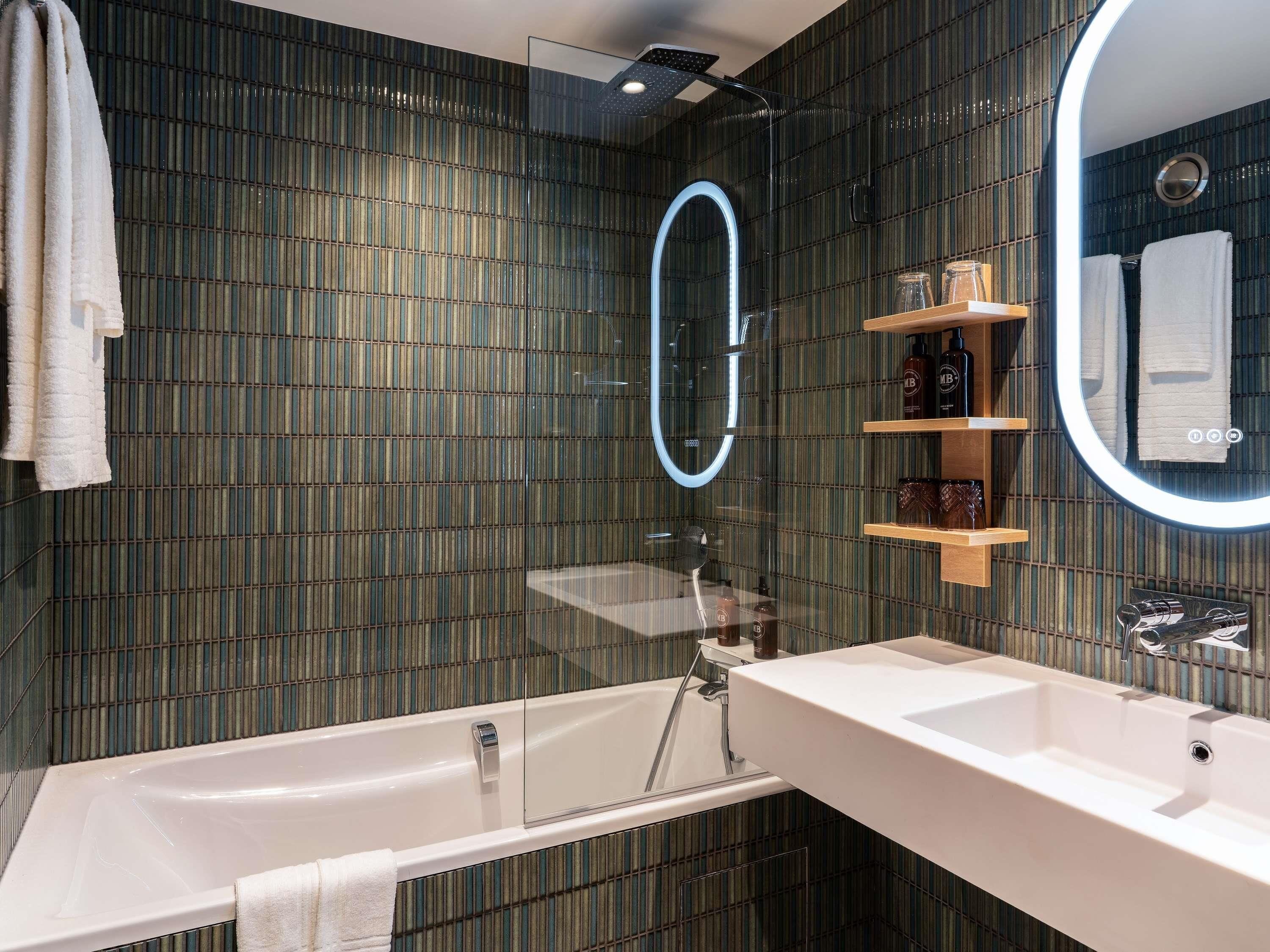 Un baño moderno con bañera, lavabo, espejo y ducha.