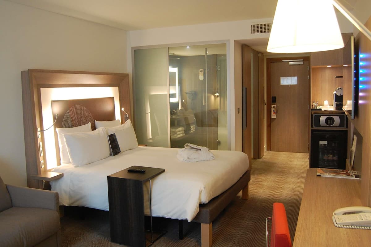 A hotel room with a bed, bedside table, chair, desk, and a telephone.