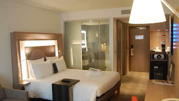 Una habitación de hotel con cama, mesita de noche, silla, escritorio y teléfono.