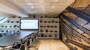 A conference room with a large screen displaying 'Bienvenue,' a wall of vintage telephones, and a ceiling with recessed lighting.