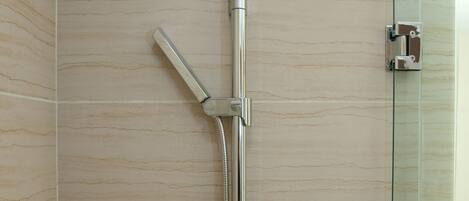 A shower with a glass enclosure, a handheld showerhead, and a wall-mounted faucet.