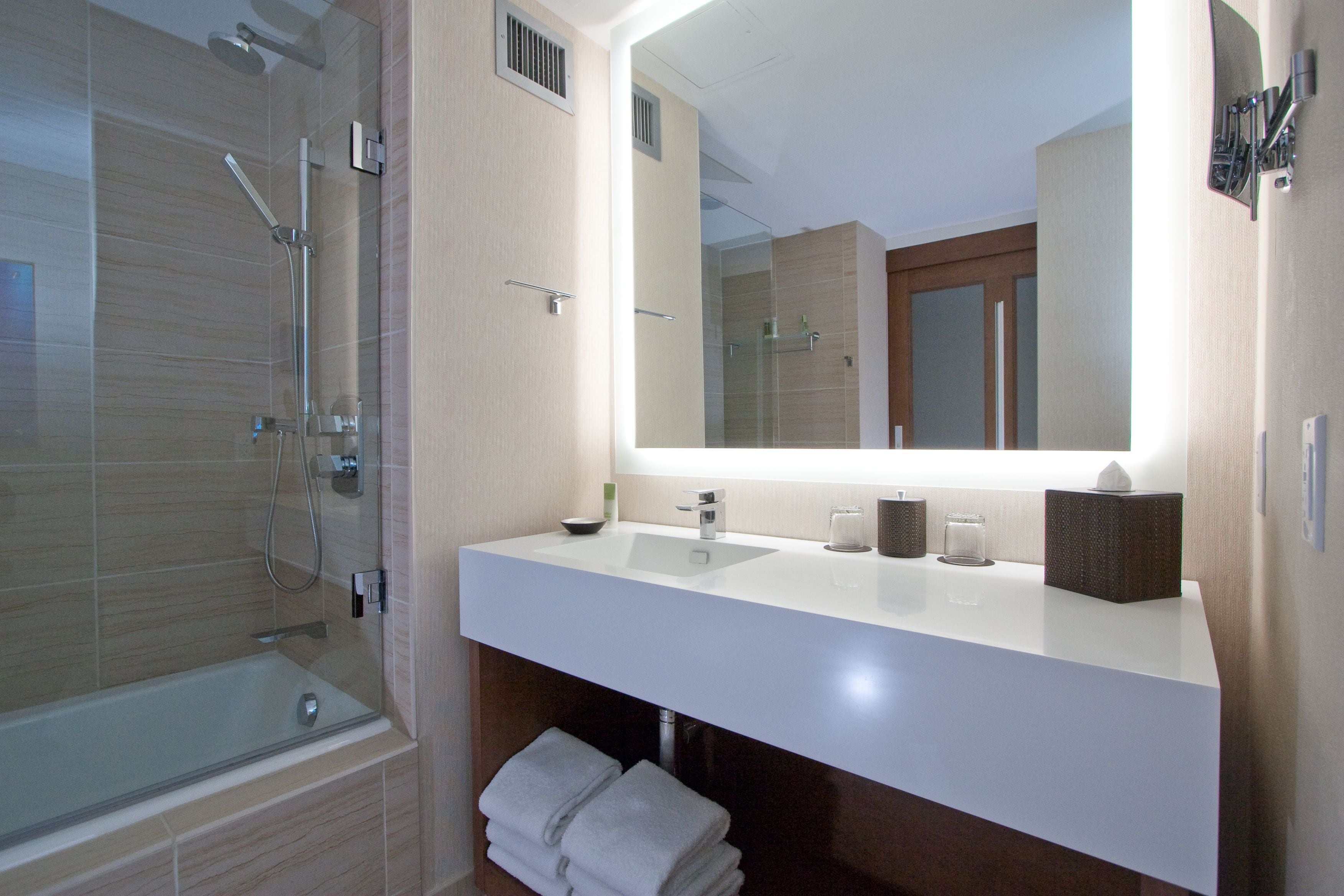 A modern bathroom with a glass-enclosed shower, a white sink, and a large mirror.