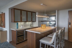 A modern kitchen with wooden cabinets, a central island, and bar stools.