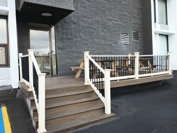 A building entrance with a wooden staircase, a metal railing, and a textured wall. - Comfort Inn & Suites Johnson City - Binghamton (Johnson City)