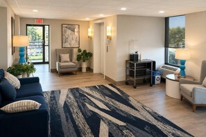 A hotel lobby with a reception desk, seating area, and a large window.