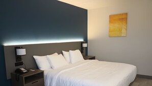 Ein modernes Hotelzimmer mit einem großen Bett, Nachttischen, einem Telefon und Wandleuchten.