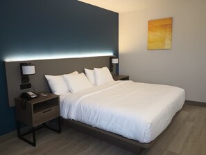 Habitación de hotel moderna con una cama grande, mesitas de noche, teléfono y lámparas de pared.