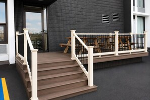 Eine Holztreppe führt zu einem Balkon mit Geländer, einer Bank und einem Tisch.