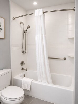 Ein Badezimmer mit Badewanne, Toilette, Dusche und Handläufe.