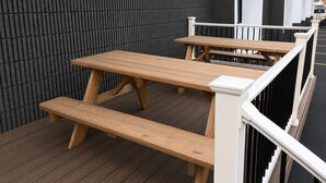 En træterrasse med picnicborde og gelænder.