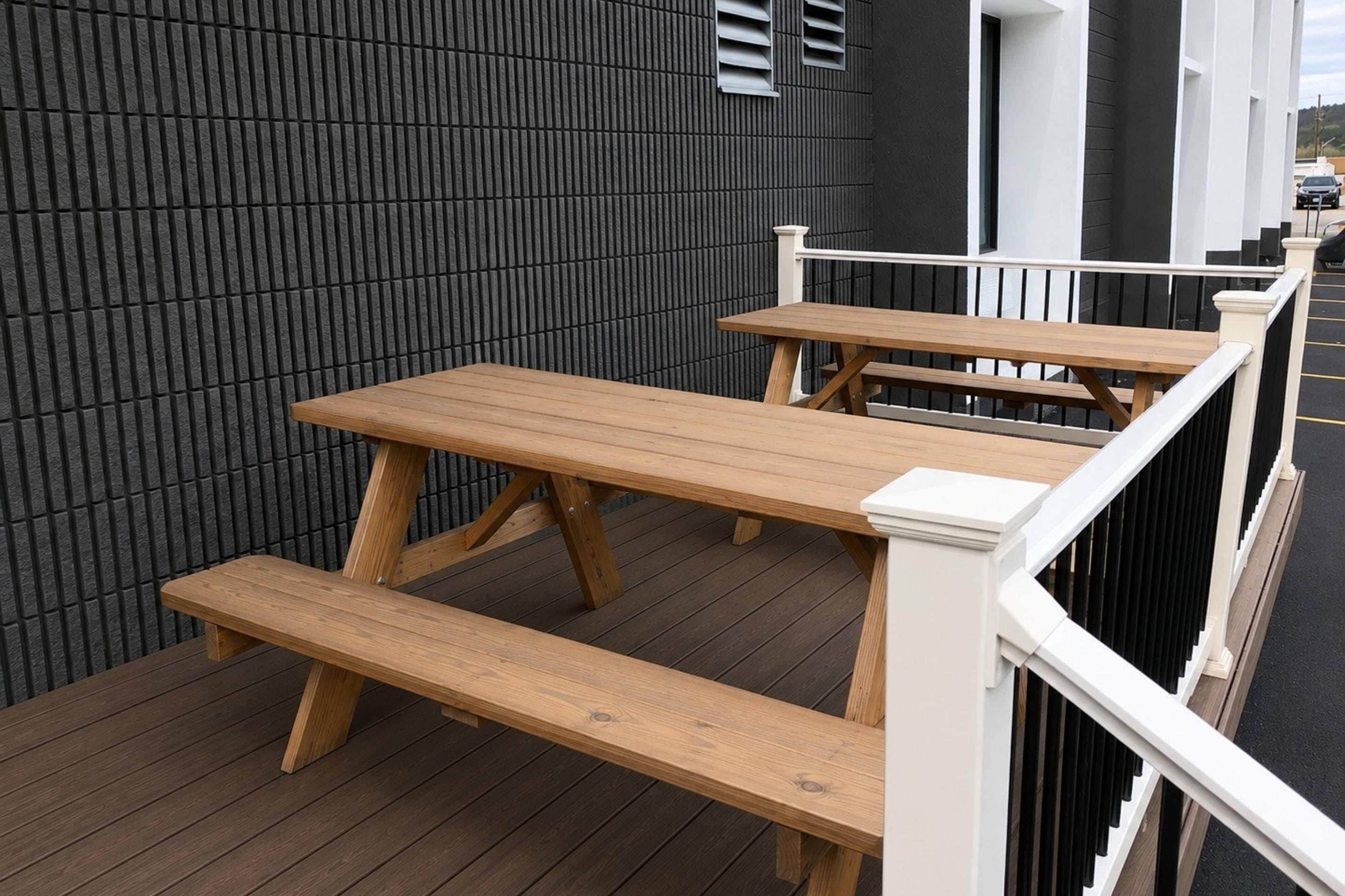 A wooden deck with benches, a railing, and a dark textured wall.