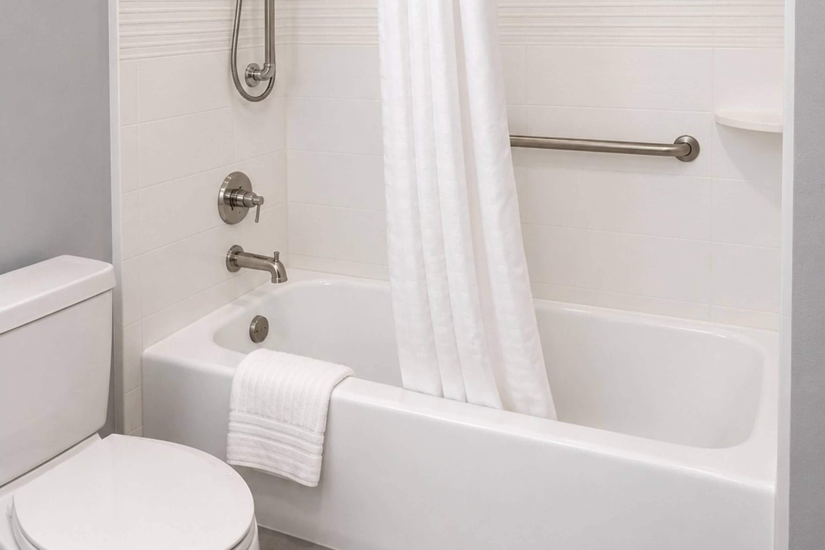 A bathroom with a white bathtub, a toilet, and a shower area.