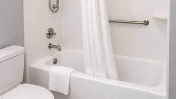 A bathroom with a white bathtub, a toilet, and a shower area.