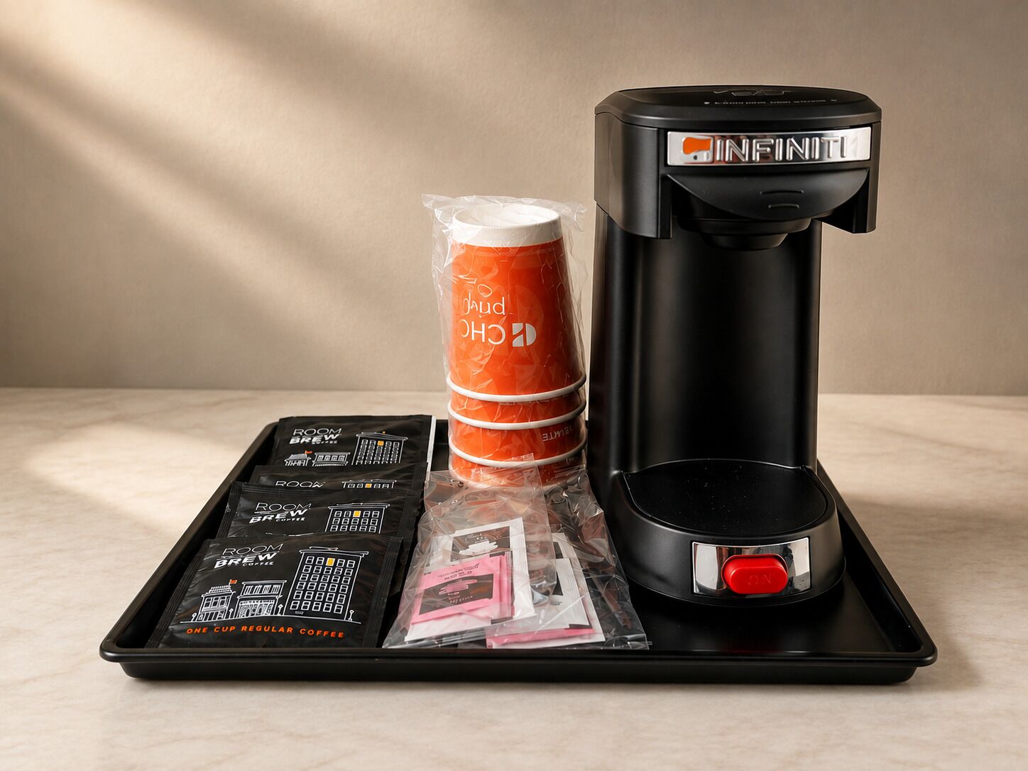 Una cafetera, una pila de cápsulas de café naranja y una bandeja con cápsulas de café y una revista.