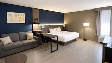 Una habitación de hotel con cama, escritorio, sofá y sillón.