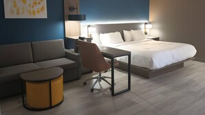 Ein Hotelzimmer mit einem Bett, einer Couch, einem Schreibtisch und einem Sessel.