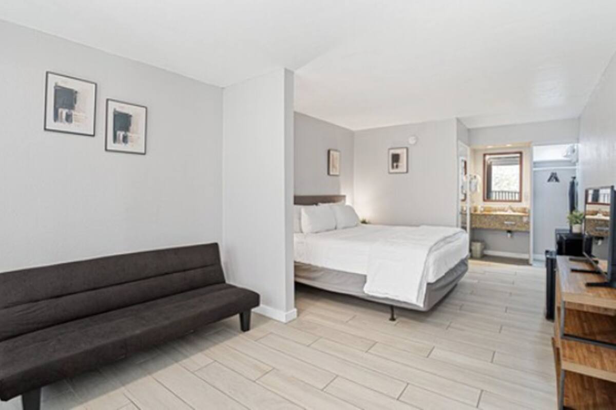 Une chambre à coucher moderne avec un lit, un banc et un petit bureau.