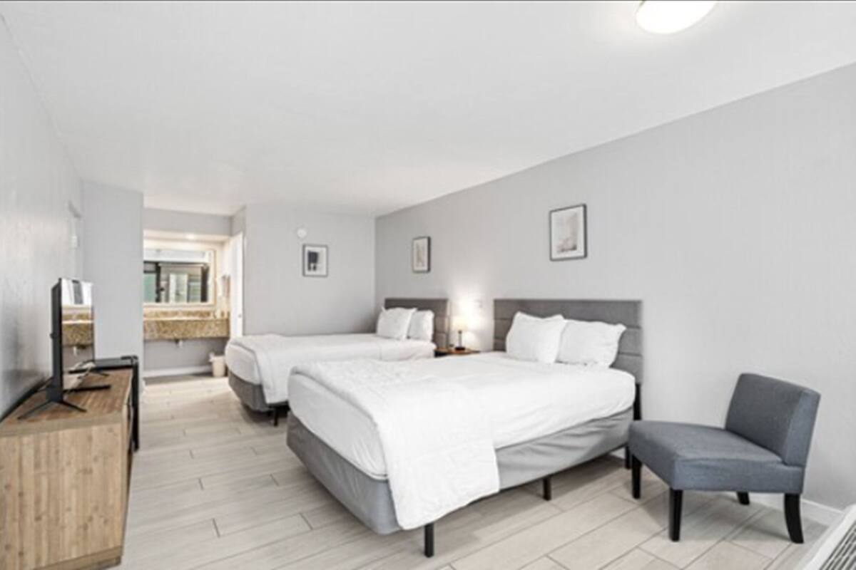 Une chambre d’hôtel moderne avec deux lits, un bureau et une chaise.