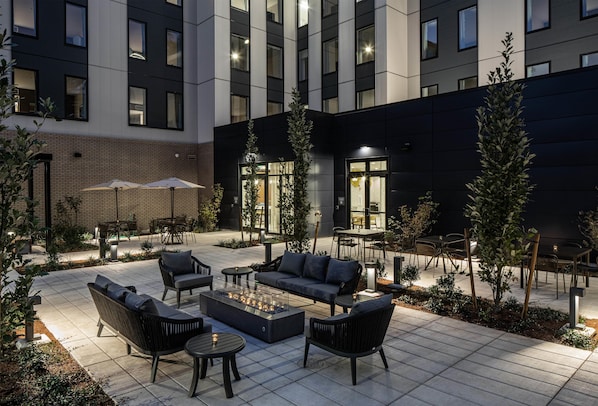A modern outdoor seating area with a fire pit, lounge chairs, and tables. - Hilton Garden Inn Wilsonville Portland (Wilsonville)