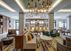 Un hall de hotel con zona de bar, asientos distribuidos y alfombra estampada.