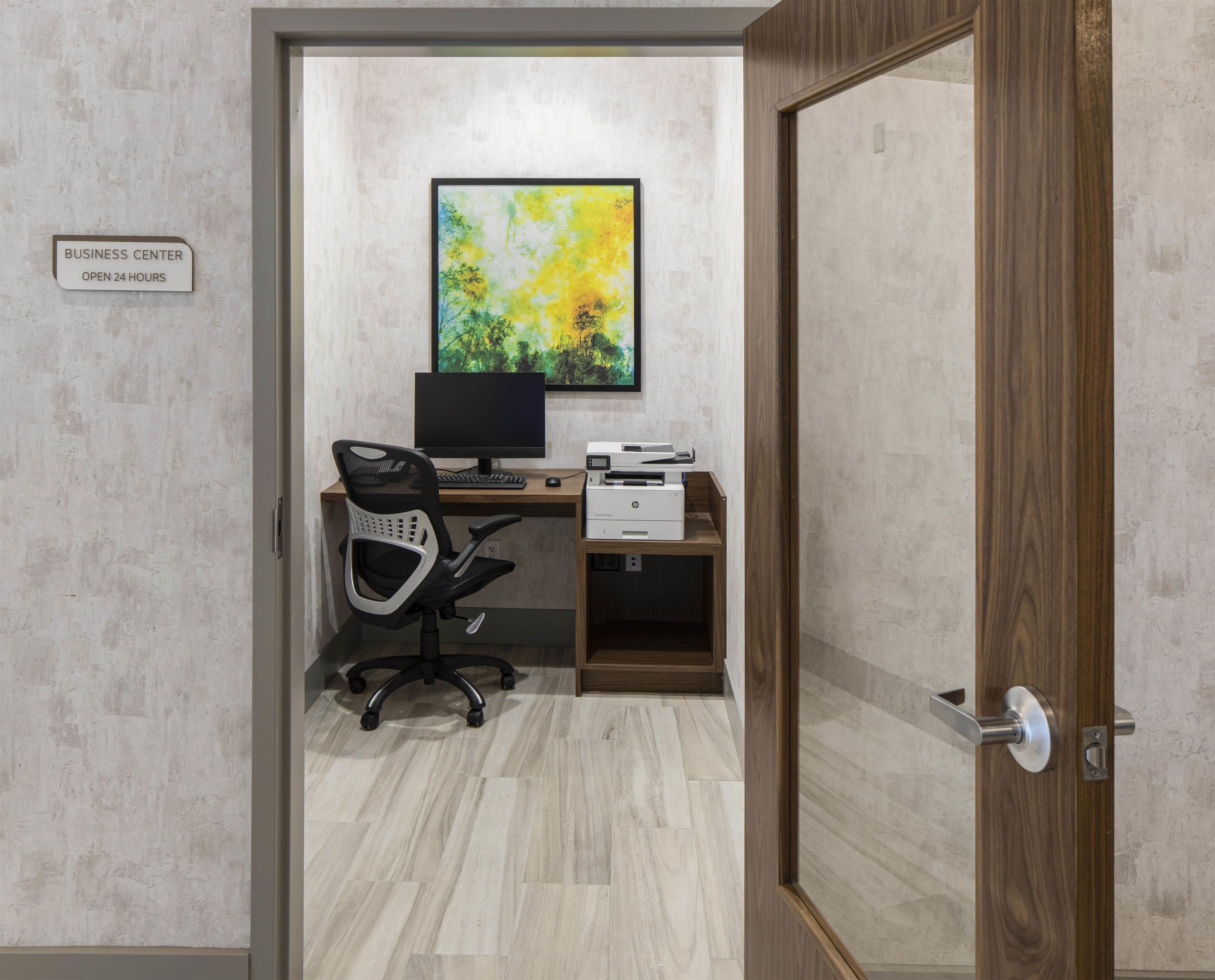 A business center with a computer, printer, and office chair.
