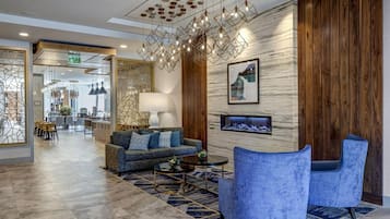 A modern hotel lobby with a sofa, chairs, a dining area, and a unique geometric chandelier.