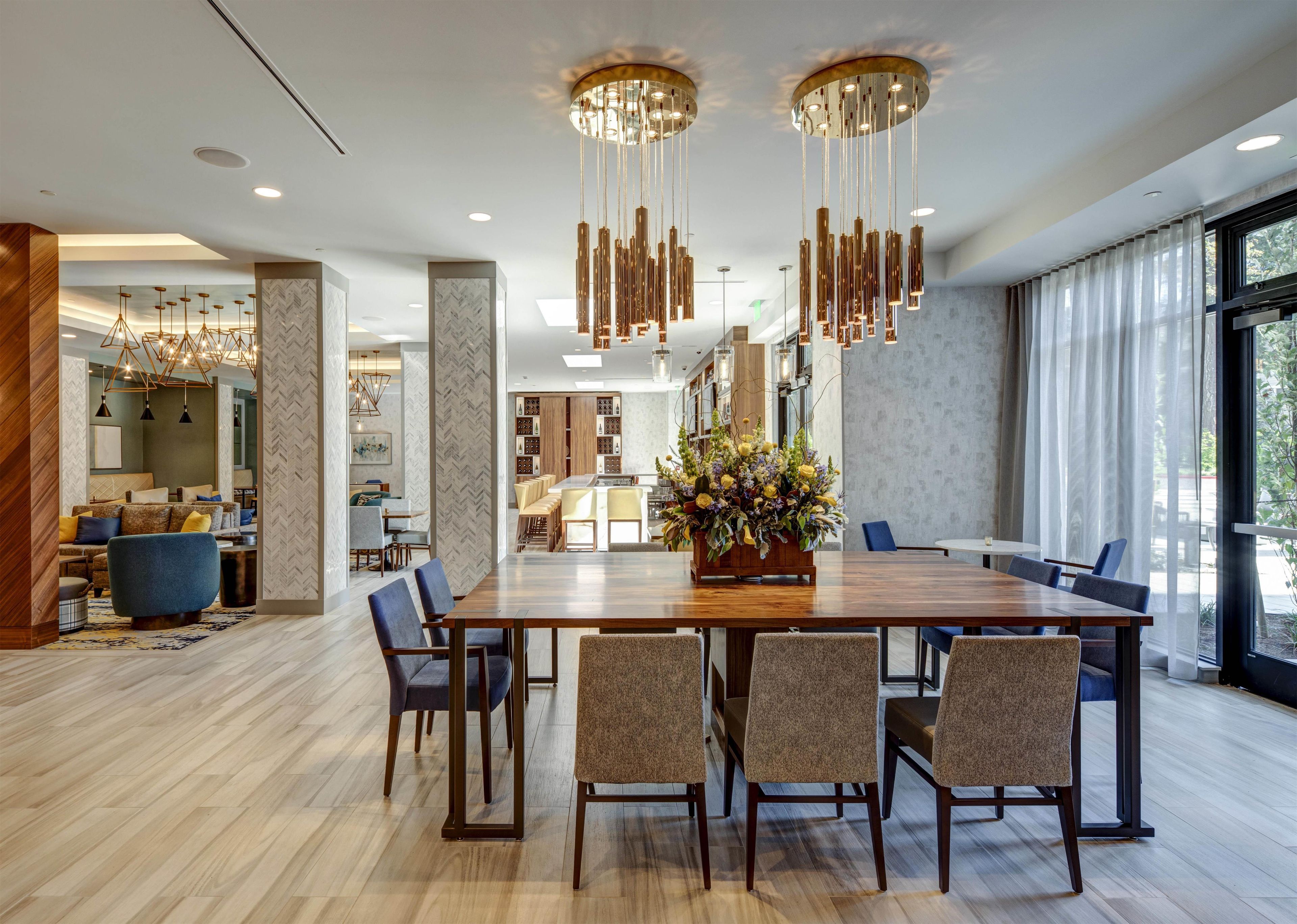A modern dining area with a wooden table, multiple chairs, and a central floral arrangement.