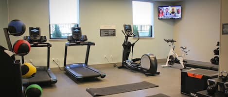 A fitness center with treadmills, an elliptical, a stationary bike, and various exercise balls.