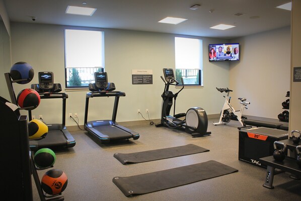 A fitness center with treadmills, an elliptical, a stationary bike, and various exercise balls.