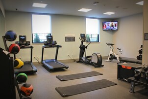 Un gimnasio con cintas de correr, elíptica, bicicleta estática y diferentes balones de ejercicio.