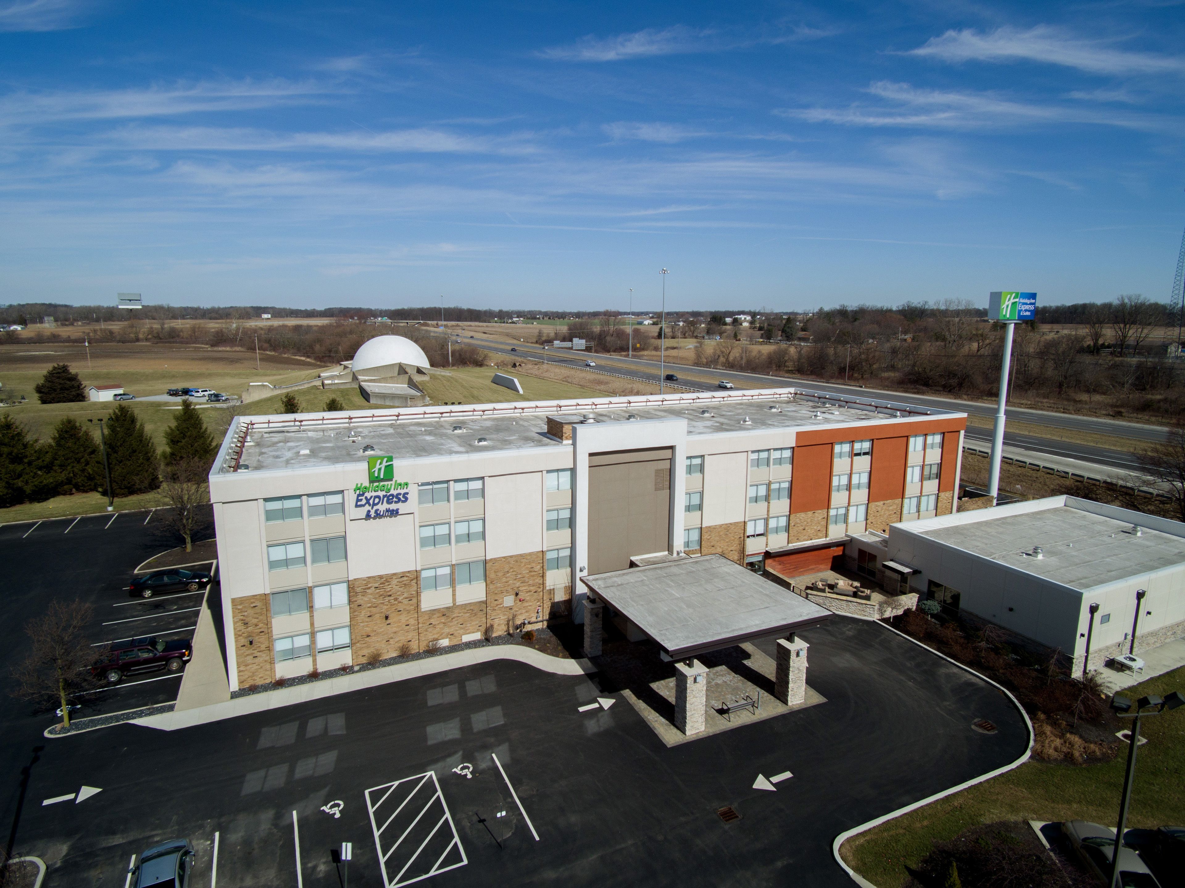 A Holiday Inn Express building with a parking lot, a dome structure, and a highway in the background.