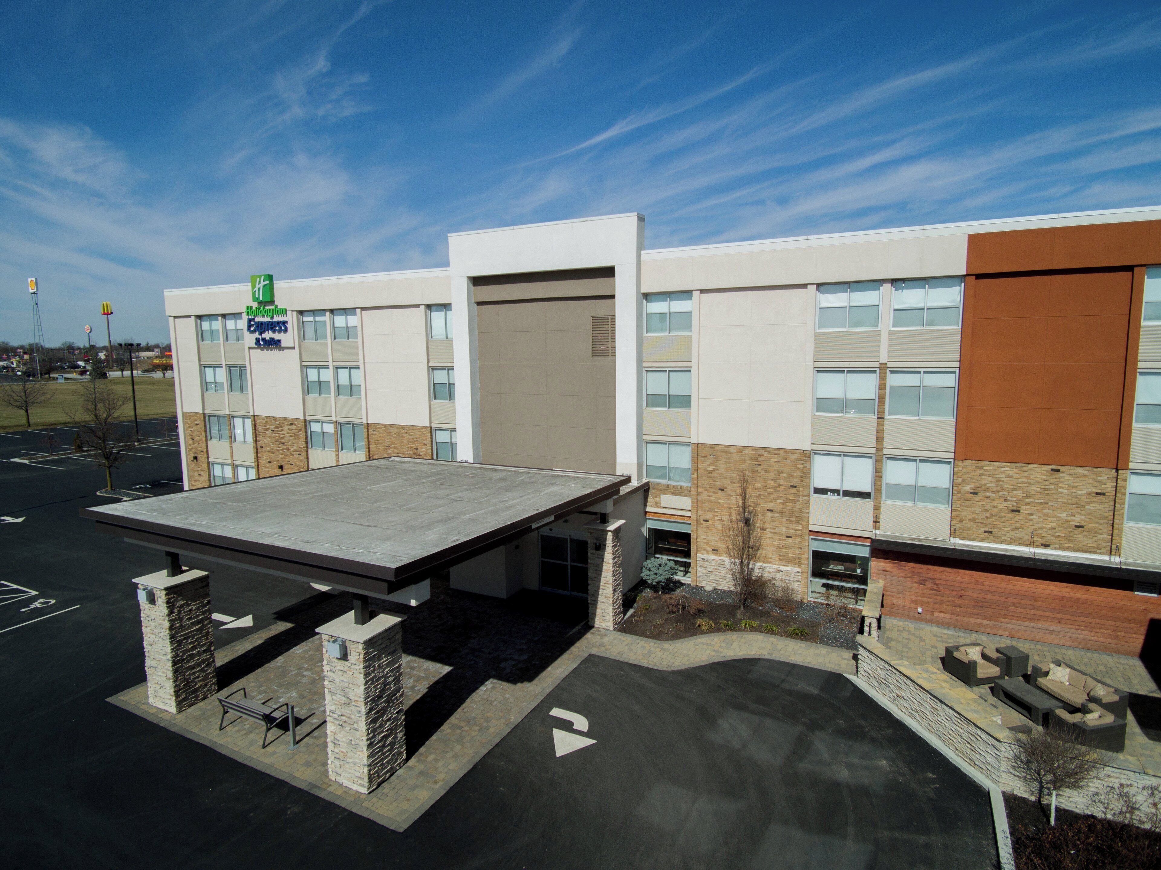 A modern hotel with a covered parking area, a landscaped front, and a clear sky.