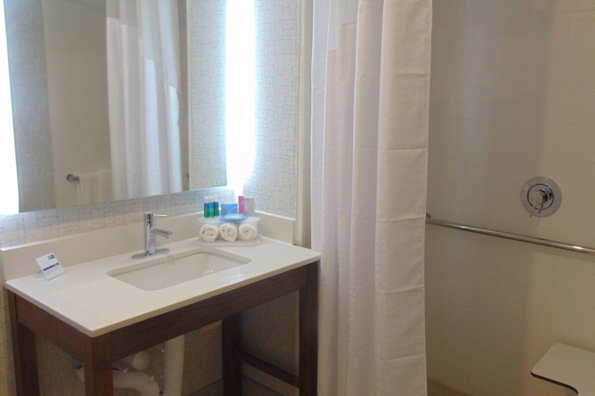 Une salle de bain équipée d’un lavabo, d’un miroir et d’un rideau de douche.